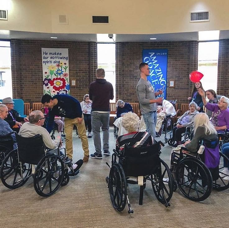 Students helping wheelchair bound seniors for PERK outing