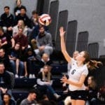 Women's volleyball game: player jumping up to hit the ball