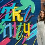 Yuri Coleman standing in front of her Trinity mural installment
