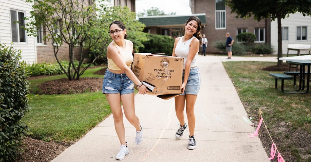 Move-In Day: students working together carrying a box outside south hall
